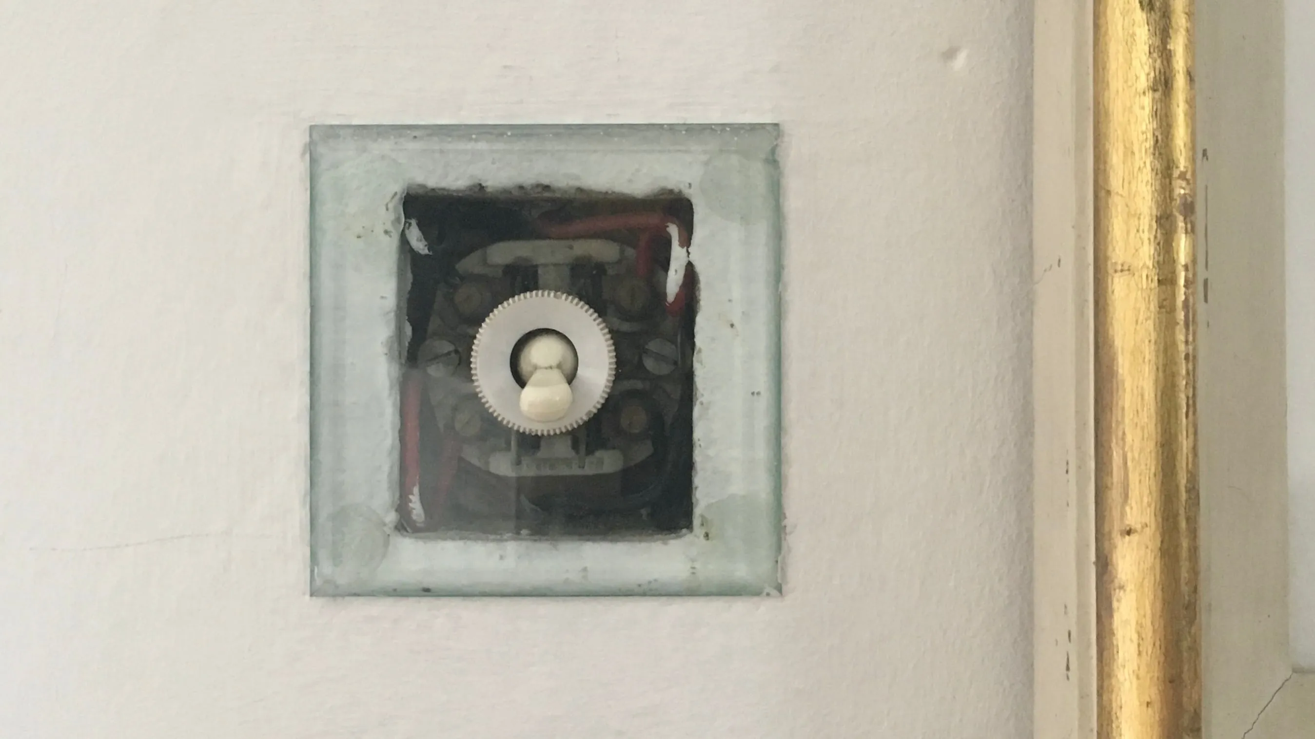 A transparent switch cover exposing the wiring in the wall.
